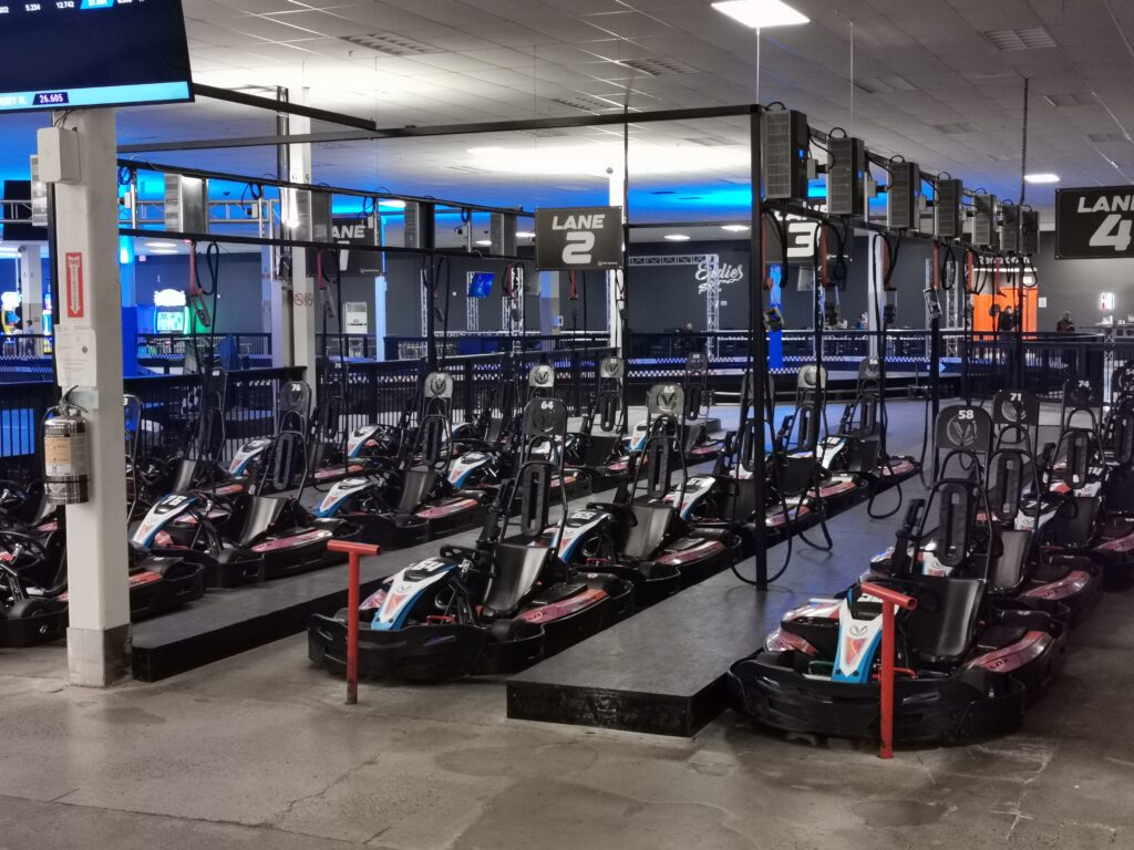 Indoor go-kart racing track with electric karts lined up in lanes, ready for use at a modern entertainment facility.