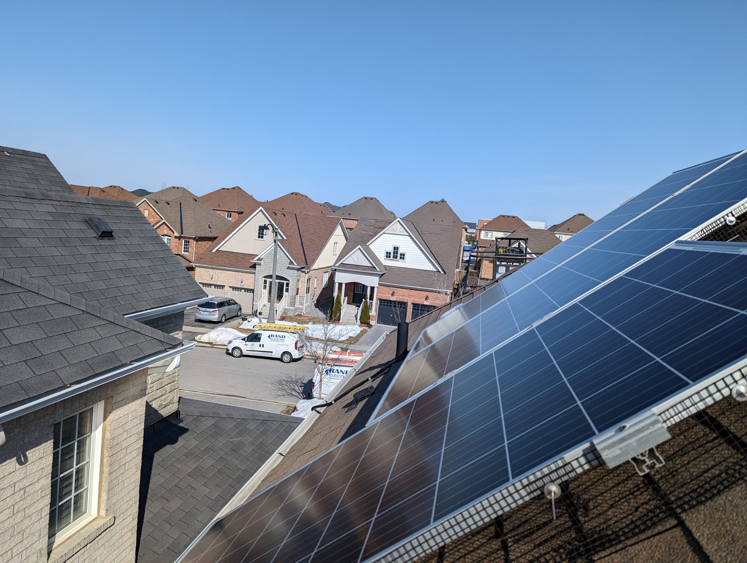 A residential rooftop with newly installed solar panels and a company work van parked on the street below.
