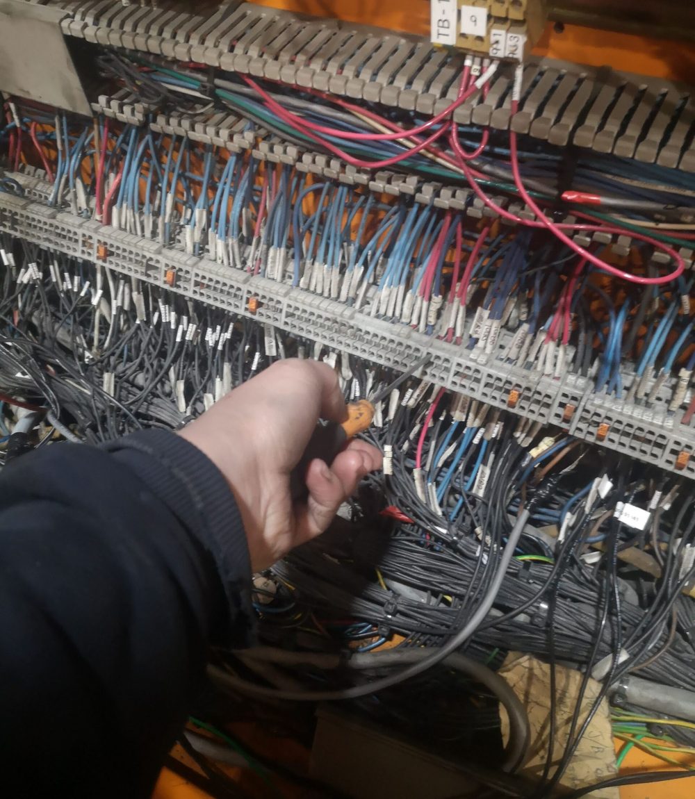 Industrial Electrical Panel Maintenance | Terminal Block Wiring Work Technician working on a complex industrial terminal block panel with multiple electrical wires and a screwdriver.