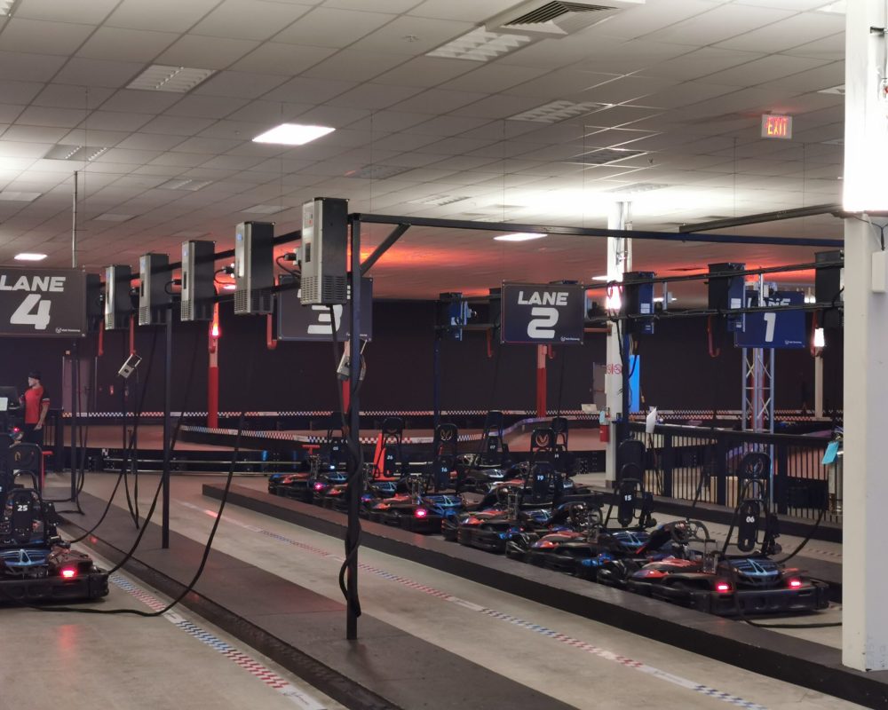 Indoor Electric Go-Kart Charging and Staging Area Indoor electric go-kart charging and staging area with multiple karts parked in lanes under charging stations