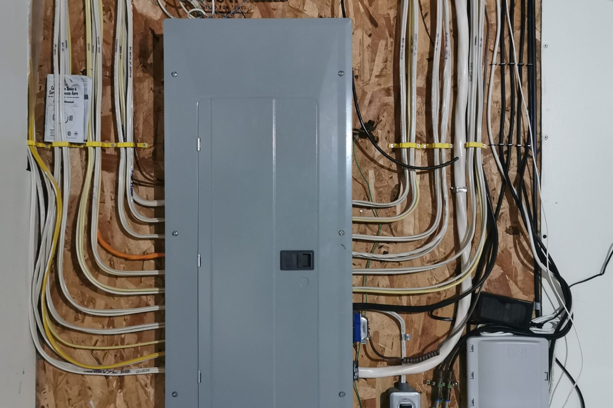 Residential Electrical Breaker Panel with Organized Wiring Residential electrical breaker panel with neatly organized wiring mounted on a plywood wall.