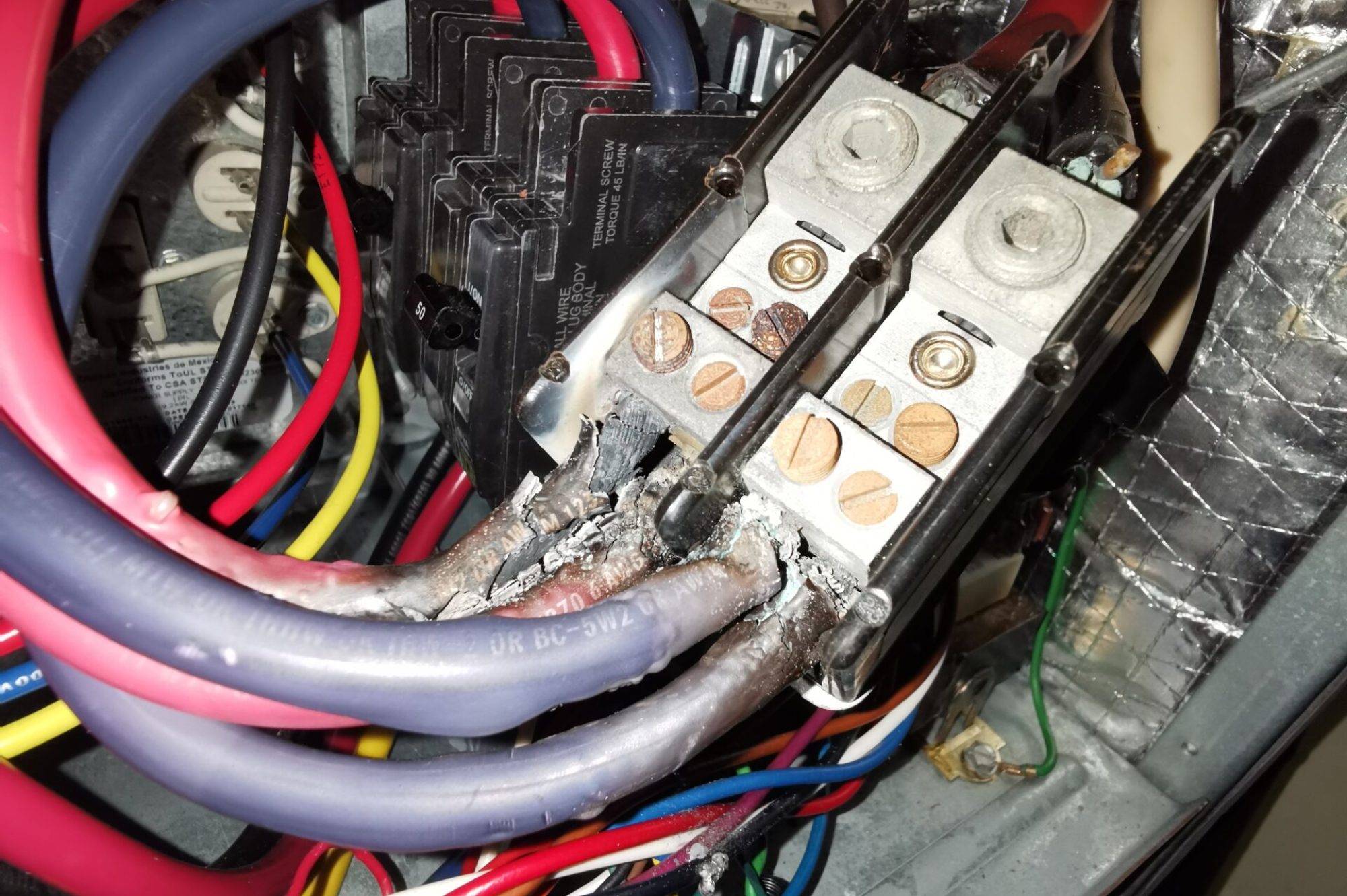 Burnt Electrical Wires and Overheated Panel Electrical panel with burnt and damaged wires showing signs of overheating and potential fire hazard.