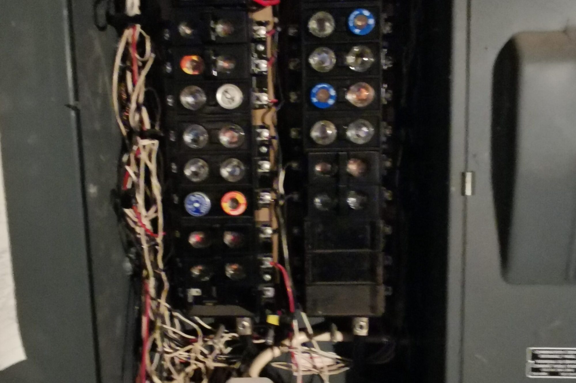 Electrical Breaker Panel with Wiring and Circuit Breakers Open electrical breaker panel showing multiple circuit breakers and wiring connections inside a distribution box.
